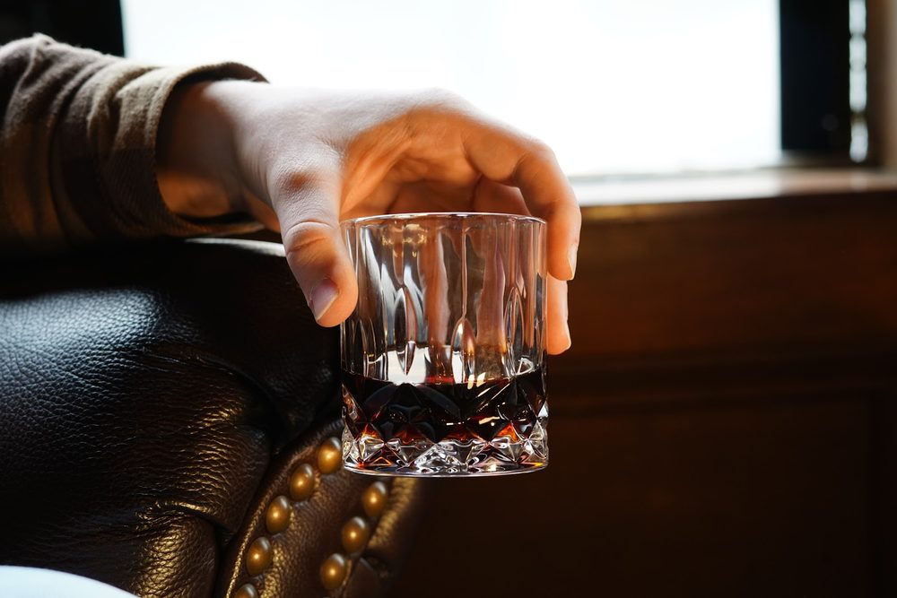 A glass of Wilhelm Cold Brew in hand on a leather chesterfield